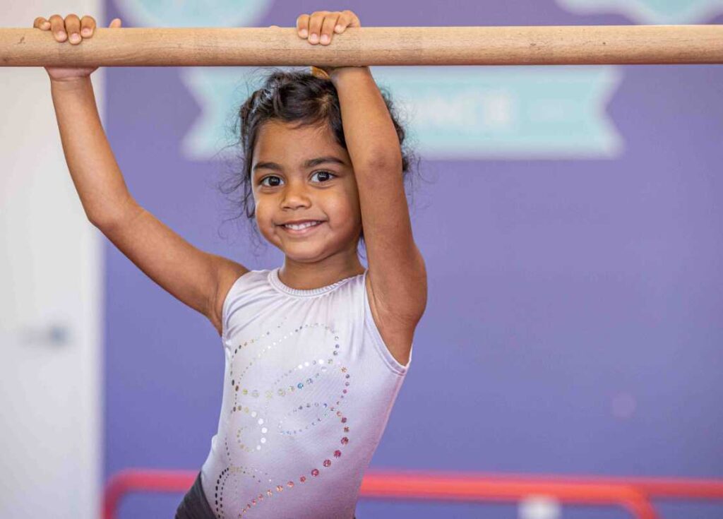 young girl handing onto a gymnastics bar