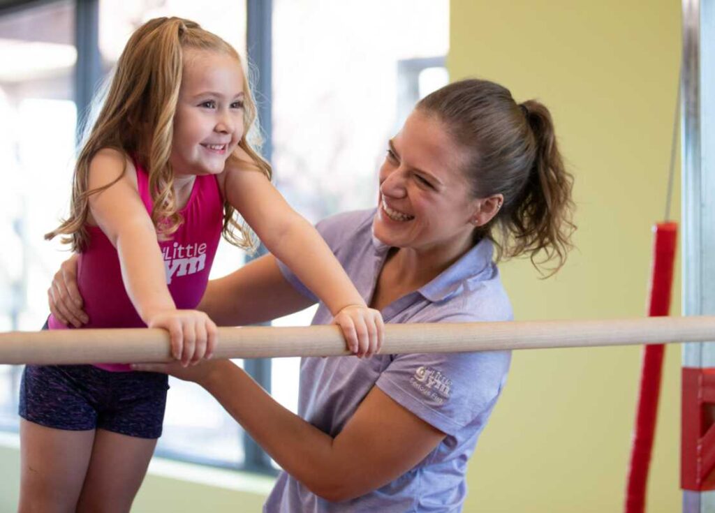 a little gym instructor guiding a girl gymnast
