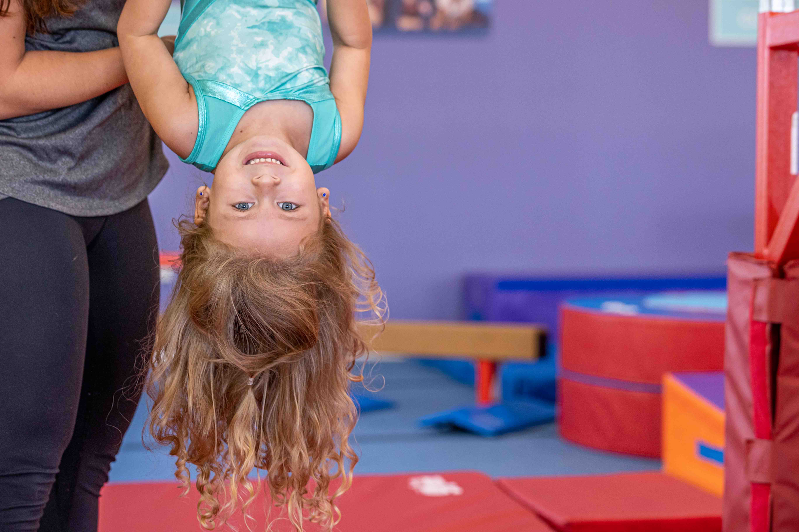 young girl doing an assisted handstand